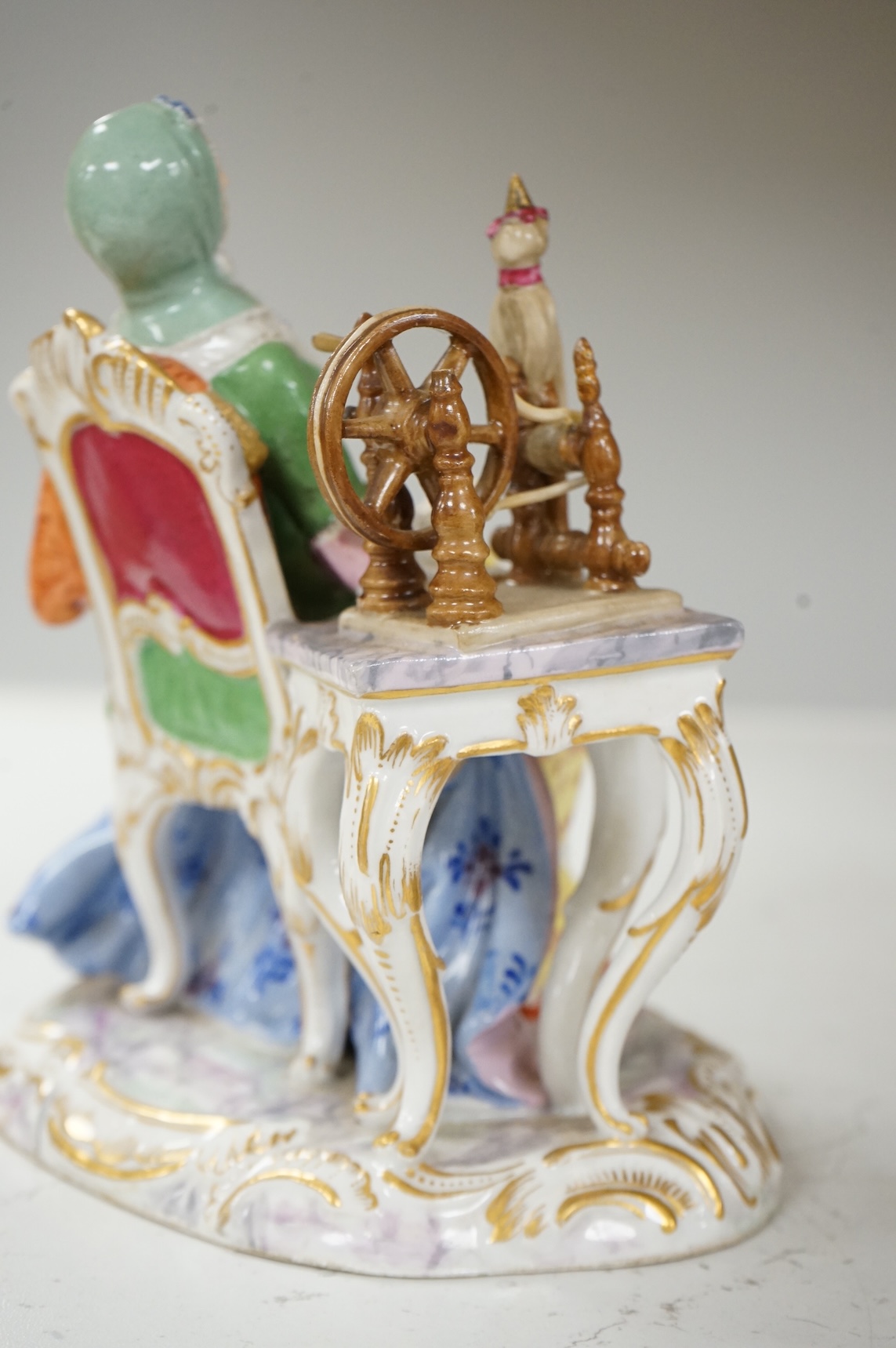 A Meissen style figure of a seated lady at her spinning wheel, 15.5cm high.